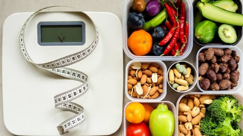 Sağlık alışverişi sepeti yanında mezura, tartı ve vitamin kutuları ile vücut analizi konsepti.